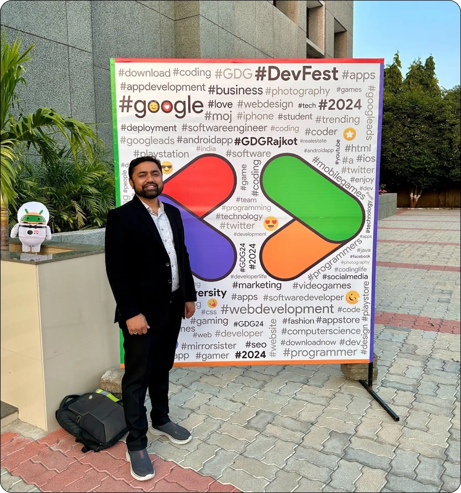 Paresh Mayani standing in front of a vibrant GDG DevFest Rajkot banner